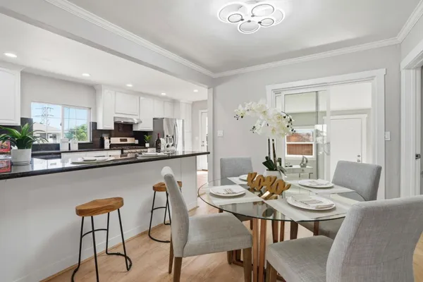 a living room with stainless steel appliances kitchen island granite countertop a dining table chairs and a refrigerator
