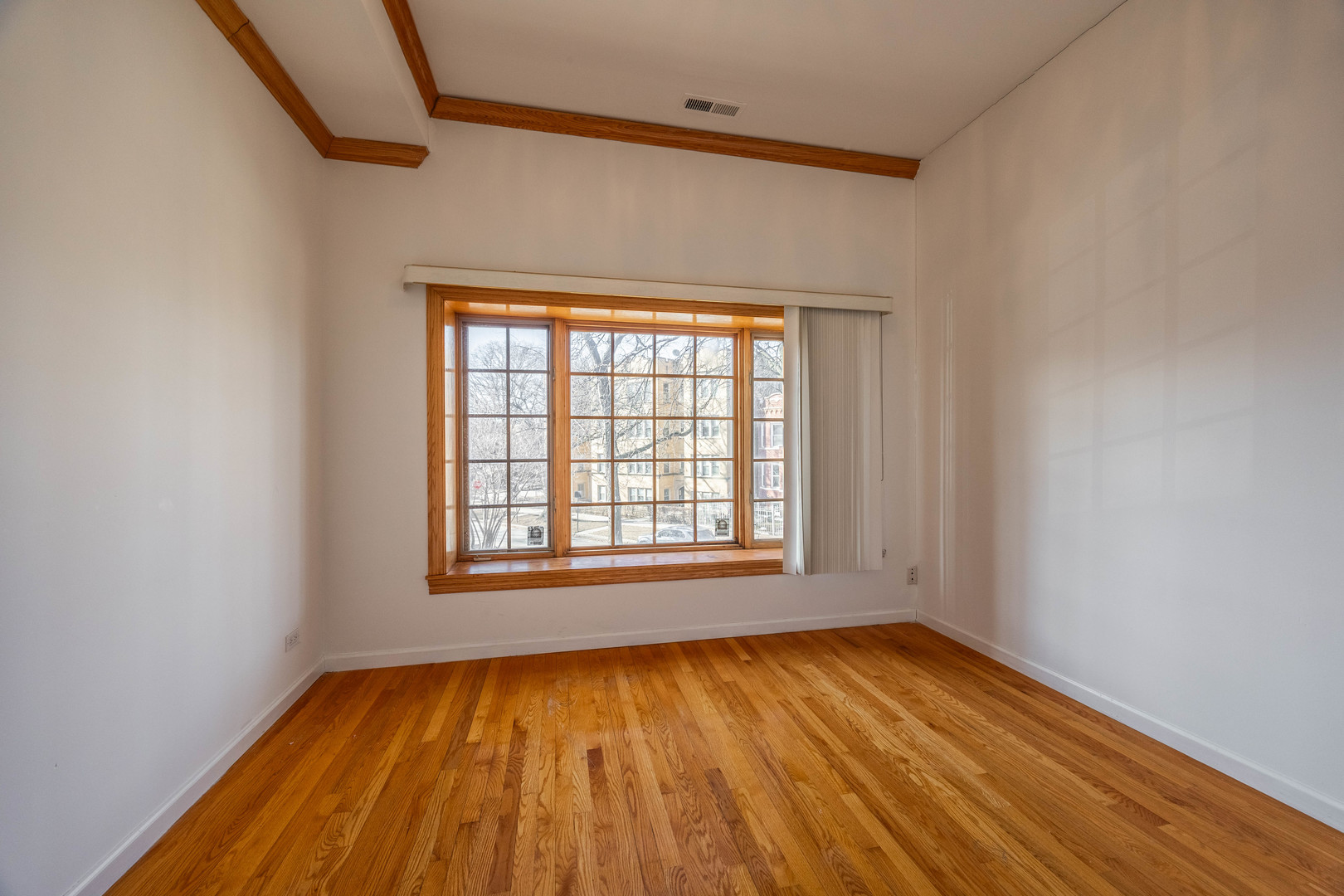 3107 North Harding Avenue, Unit 2W Chicago, IL 60618 - Photo 8 of 14 a view of an empty room with wooden floor and a window