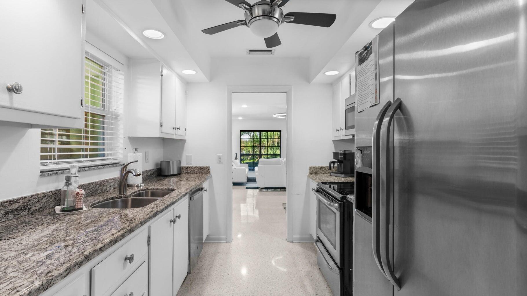 410 Venetian Drive Delray Beach, FL 33483 - Photo 15 of 28 a kitchen with stainless steel appliances granite countertop a sink stove and refrigerator