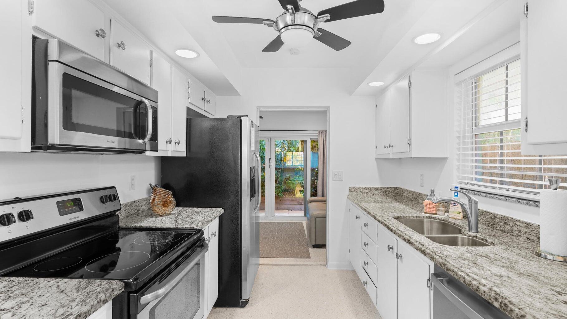 410 Venetian Drive Delray Beach, FL 33483 - Photo 16 of 28 a kitchen with stainless steel appliances granite countertop a stove sink microwave and refrigerator