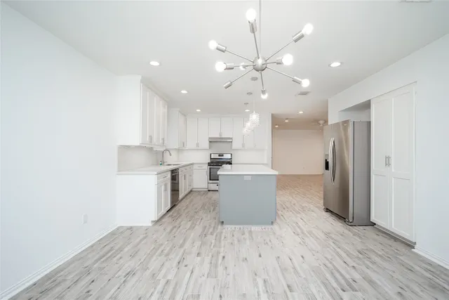 a large kitchen with a wooden floor and stainless steel appliances