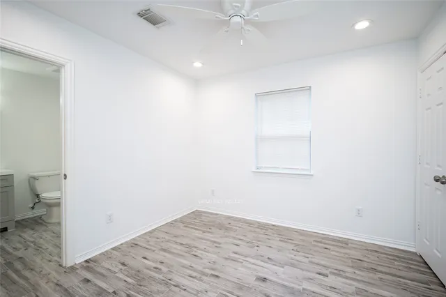 an empty room with wooden floor and a ceiling fan