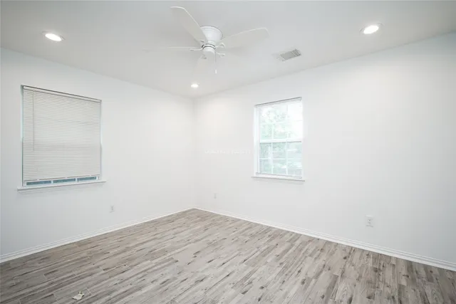 an empty room with wooden floor and windows
