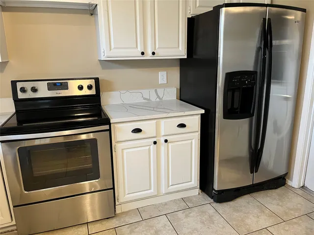 a kitchen with granite countertop white cabinets and stainless steel appliances