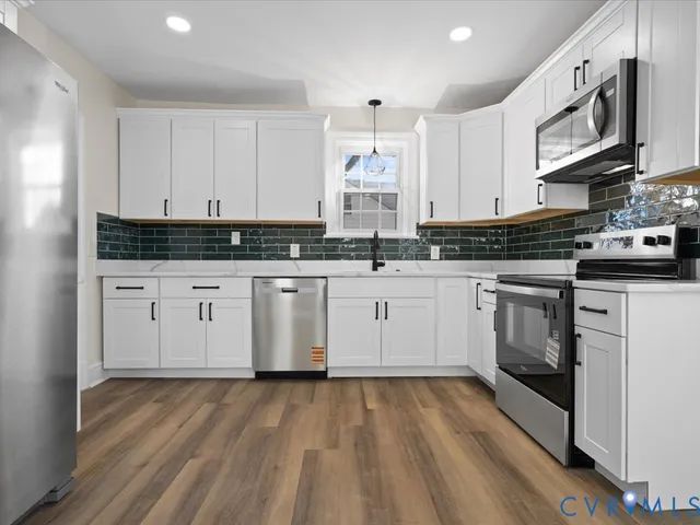 a kitchen with stainless steel appliances granite countertop a stove a sink and white cabinets