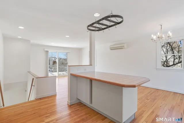 a kitchen with stainless steel appliances granite countertop a refrigerator a sink dishwasher a stove and white countertops with wooden floor