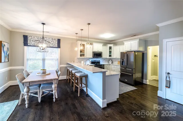 a kitchen with refrigerator a sink dishwasher a dining table and chairs with wooden floor