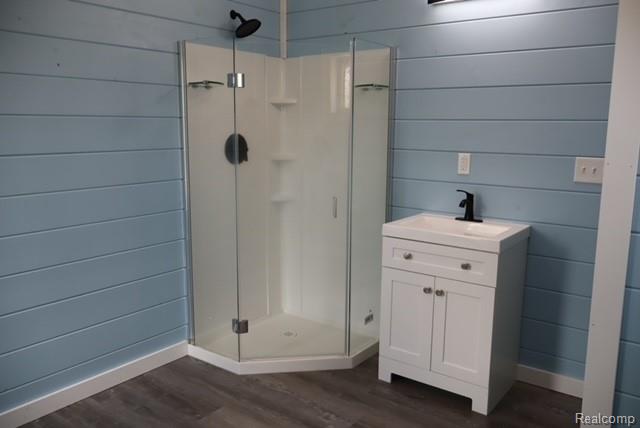 1545 South La Chance Road Lake City, MI 49651 - Photo 36 of 51 Full bath with wooden walls, a shower stall, vanity, and dark wood-style flooring