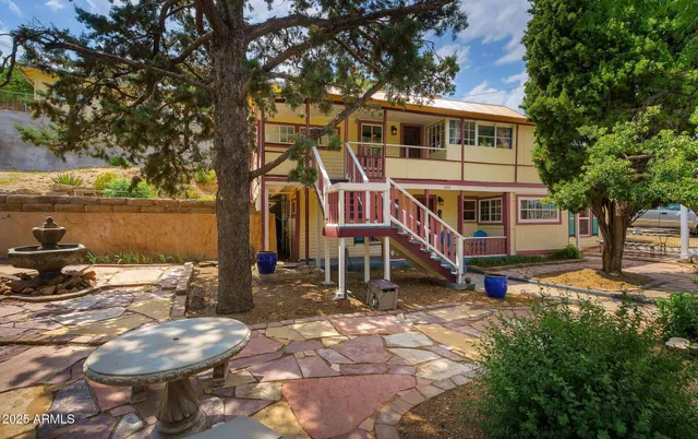 a view of a blue house with yard and sitting area