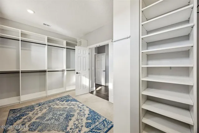 a walk in closet with wooden floor
