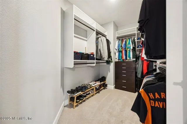 a view of walk in closet with clothes and shoes