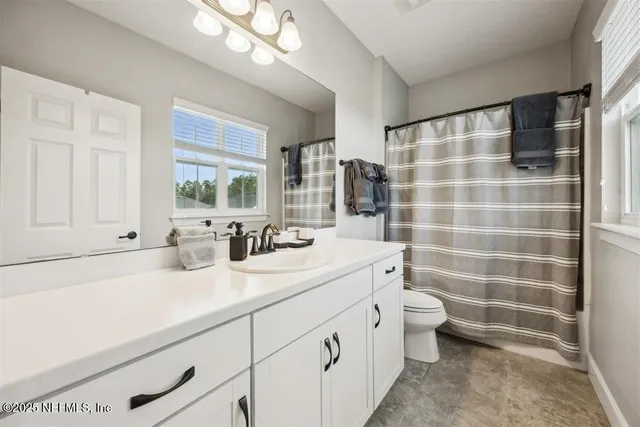 a bathroom with a sink a toilet a mirror and shower