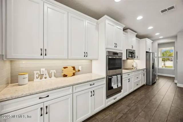 a large kitchen with stainless steel appliances granite countertop a lot of counter space and wooden floor