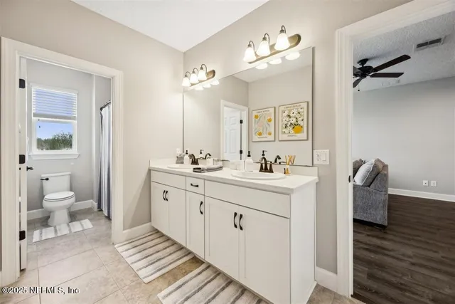 a spacious bathroom with a double vanity sink a mirror and a toilet