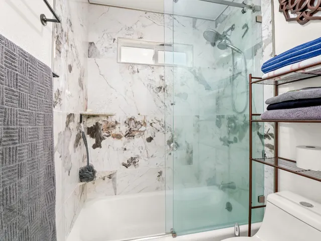 a bedroom with a large bed a flat tv screen and a potted plant