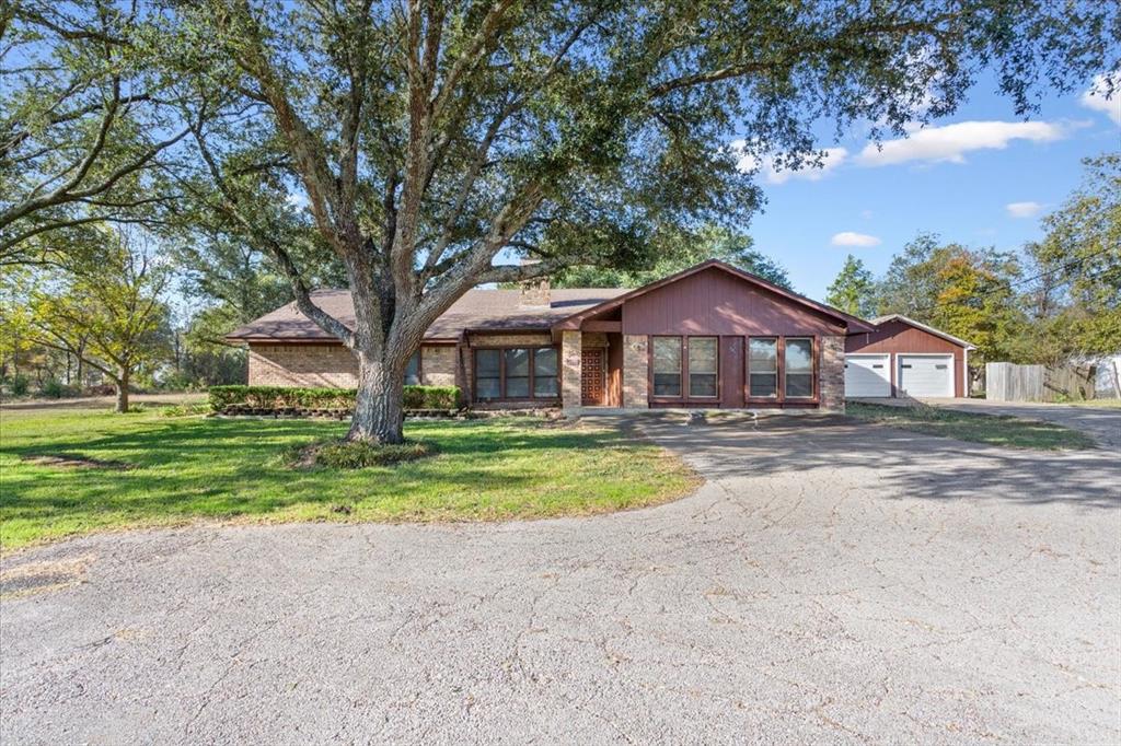 View of front of property with brick siding, a front lawn, a chimney, and driveway