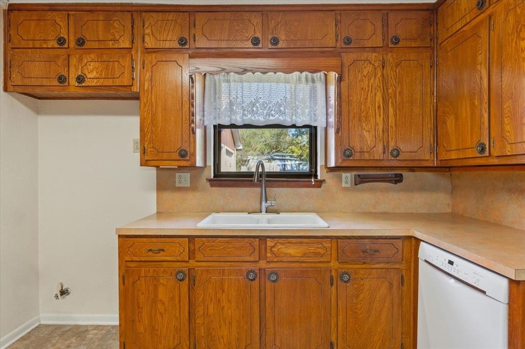 208 South Hedwig Street Riesel, TX 76682 - Photo 15 of 31 Kitchen featuring brown cabinetry, dishwasher, and light countertops