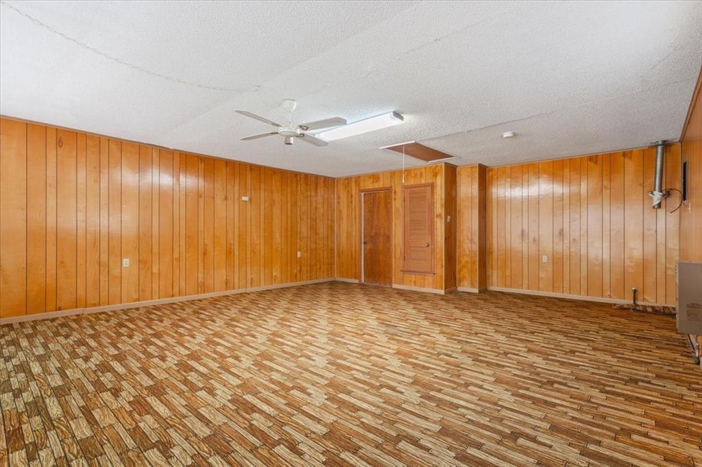 208 South Hedwig Street Riesel, TX 76682 - Photo 18 of 31 Spare room featuring wood walls, ceiling fan, light wood-style flooring, and a textured ceiling