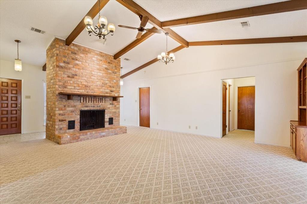 208 South Hedwig Street Riesel, TX 76682 - Photo 7 of 31 Unfurnished living room featuring beamed ceiling, a chandelier, a fireplace, light carpet, and a ceiling fan