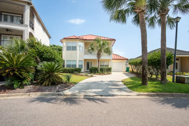 a view of a house with a yard and palm trees
