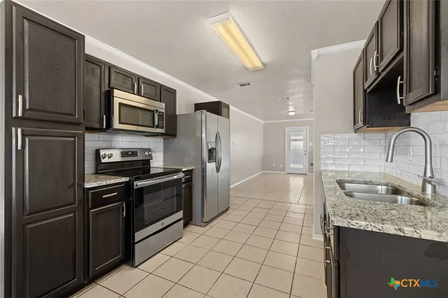 a kitchen with stainless steel appliances granite countertop a refrigerator a stove a sink and a microwave