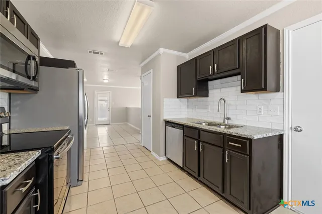 a kitchen with stainless steel appliances granite countertop a sink a stove and a refrigerator