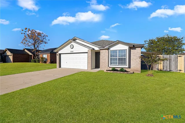 a view of a house with a big yard plants and large tree