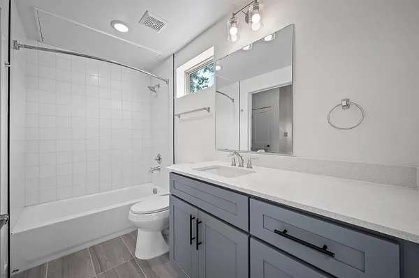 a bathroom with a granite countertop sink a toilet a mirror and shower