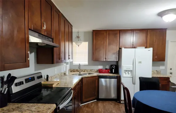 a kitchen with a refrigerator a stove a sink dishwasher and wooden cabinets with wooden floor