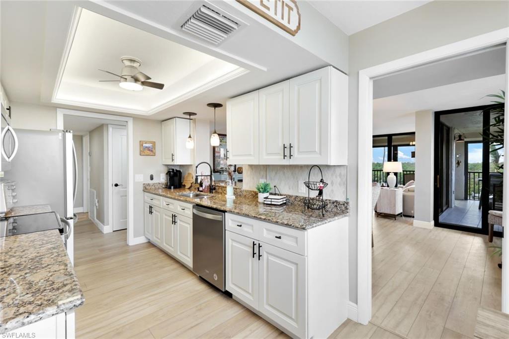 17 Bluebill Avenue, Unit 206 Naples, FL 34108 - Photo 14 of 30 Kitchen with light stone countertops, light wood-type flooring, pendant lighting, and white cabinets