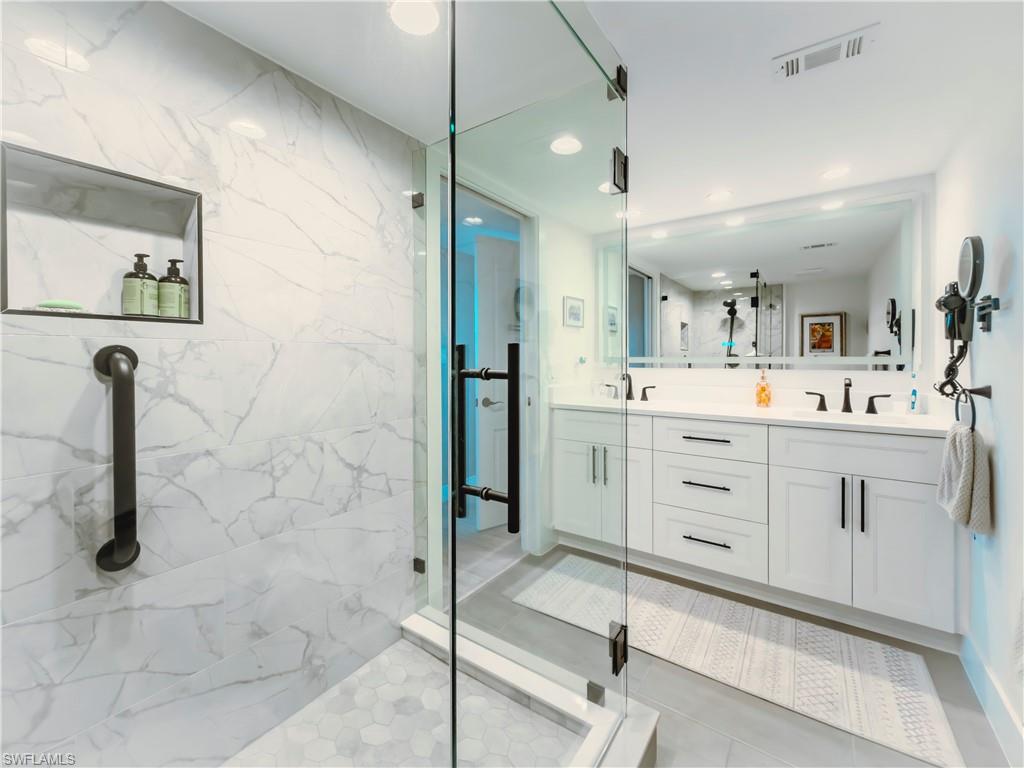17 Bluebill Avenue, Unit 206 Naples, FL 34108 - Photo 23 of 44 a spacious bathroom with a shower a sink and mirror