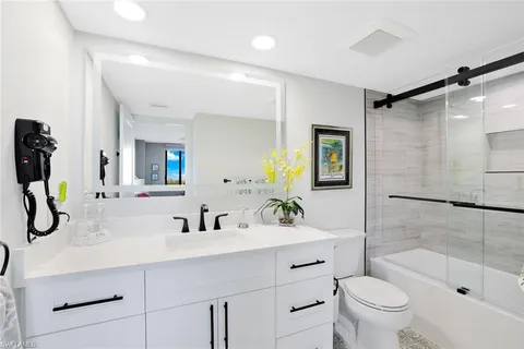 a bathroom with a tub shower sink and a mirror