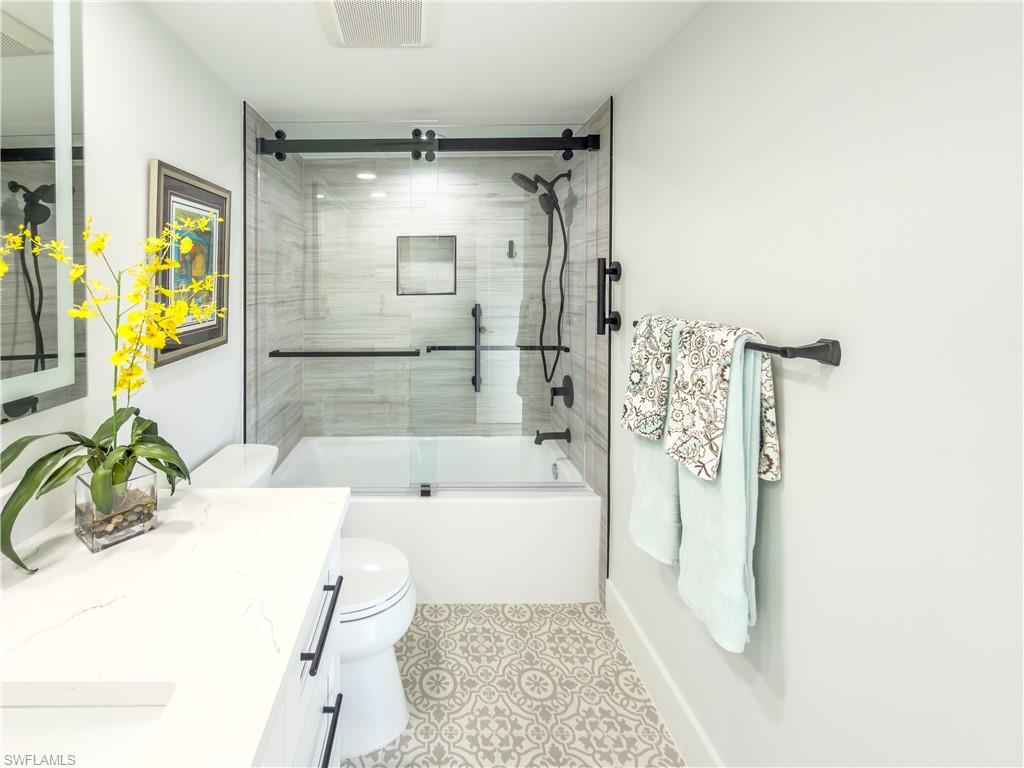 17 Bluebill Avenue, Unit 206 Naples, FL 34108 - Photo 28 of 44 a bathroom with a tub shower sink and a mirror