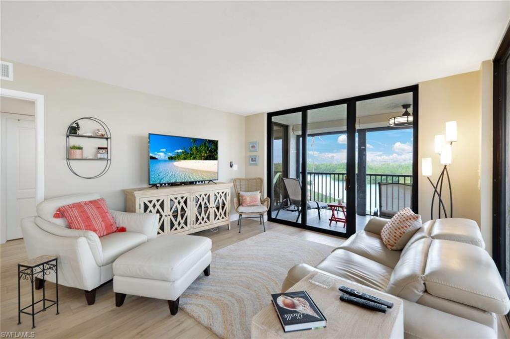 17 Bluebill Avenue, Unit 206 Naples, FL 34108 - Photo 6 of 30 Living area with wood finished floors and a wall of windows