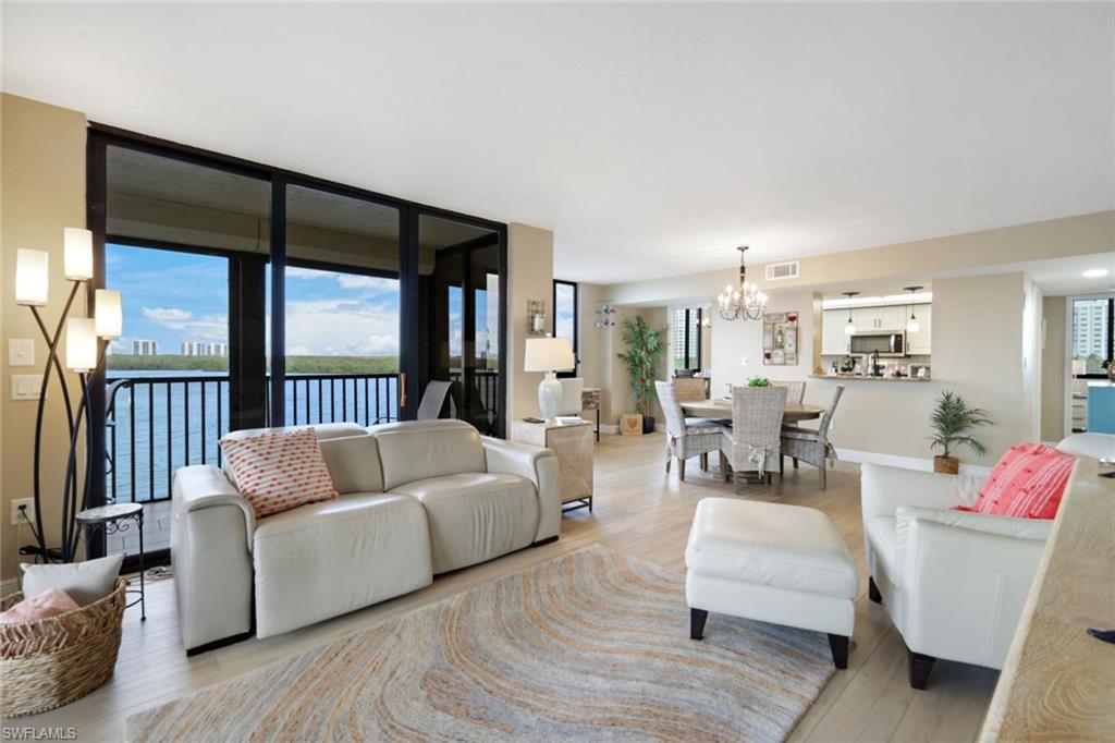 17 Bluebill Avenue, Unit 206 Naples, FL 34108 - Photo 7 of 30 Living room featuring wood finished floors, a water view, and a chandelier