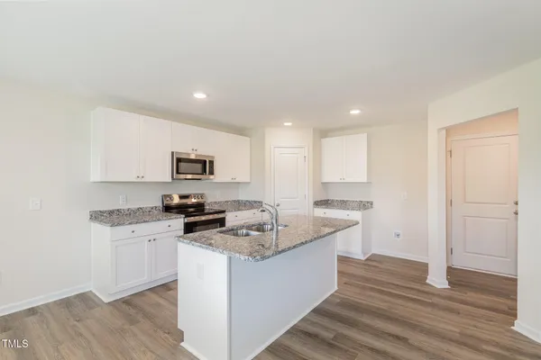a kitchen with granite countertop a sink stove and refrigerator