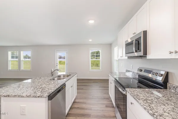 a kitchen with stainless steel appliances granite countertop a sink stove and microwave