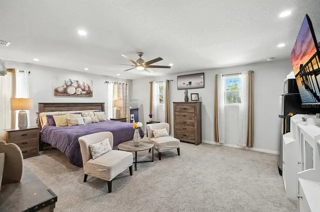 a spacious bedroom with a bed furniture and a flat screen tv