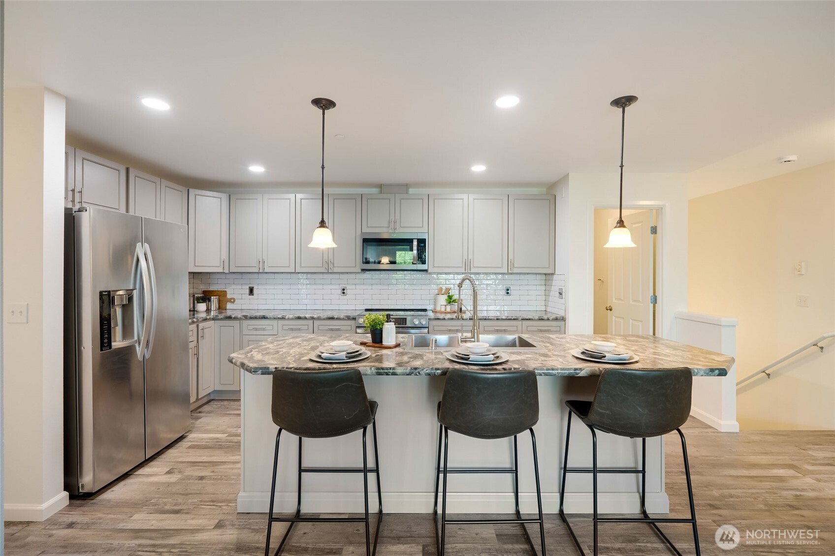4678 Wade Street, Unit 201 Bellingham, WA 98226 - Photo 7 of 25 a kitchen with stainless steel appliances kitchen island granite countertop a dining table chairs and white cabinets