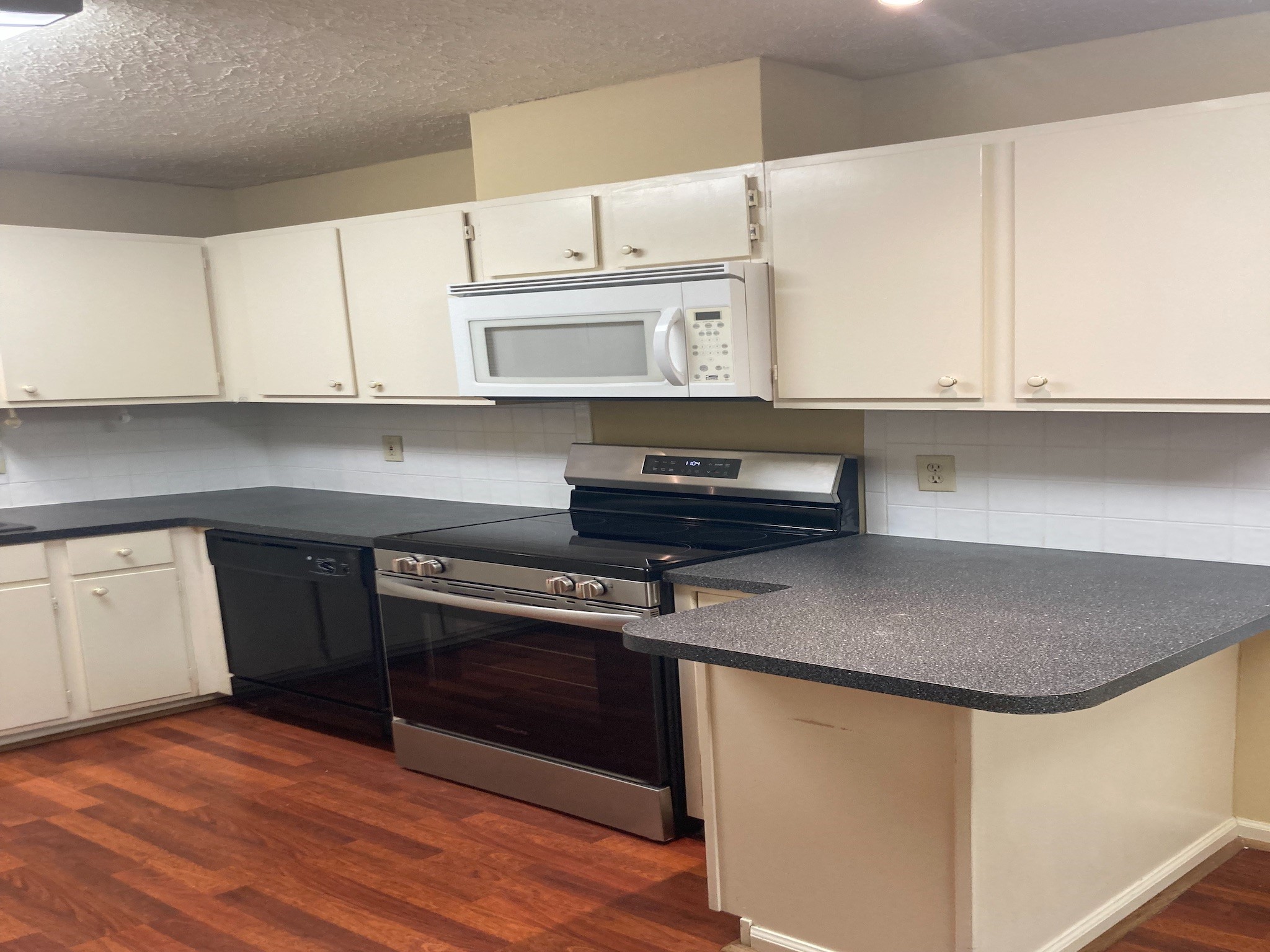 4921 Maxie Street, Unit 1/2 Houston, TX 77007 - Photo 4 of 14 a kitchen with stainless steel appliances granite countertop a sink dishwasher a stove and white cabinets with wooden floor