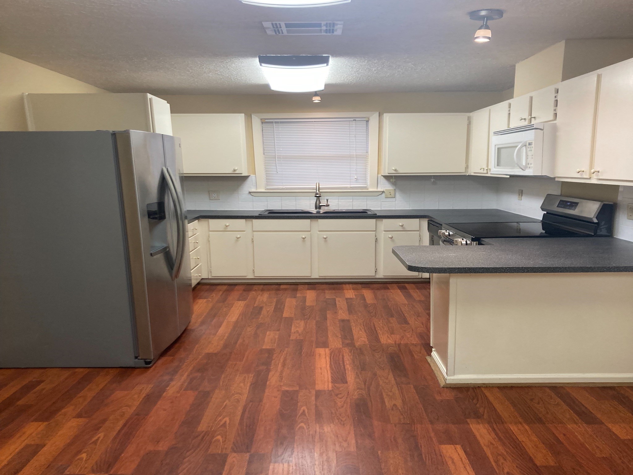 4921 Maxie Street, Unit 1/2 Houston, TX 77007 - Photo 5 of 14 a kitchen with stainless steel appliances granite countertop a refrigerator a sink dishwasher a stove and white countertops with wooden floor