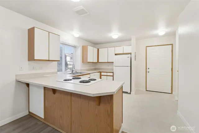 a kitchen with stainless steel appliances a sink a stove a refrigerator cabinets and a window