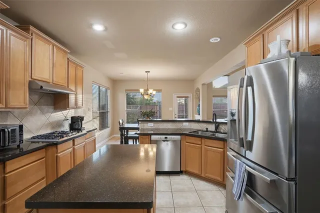 a kitchen with stainless steel appliances granite countertop a refrigerator a sink a stove and white cabinets