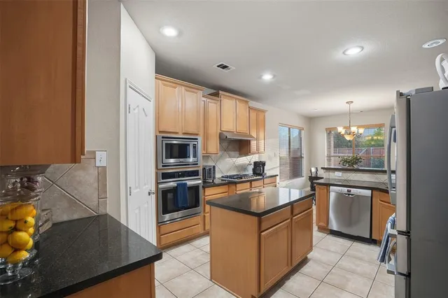 a kitchen with stainless steel appliances granite countertop a stove top oven a sink a refrigerator and white cabinets