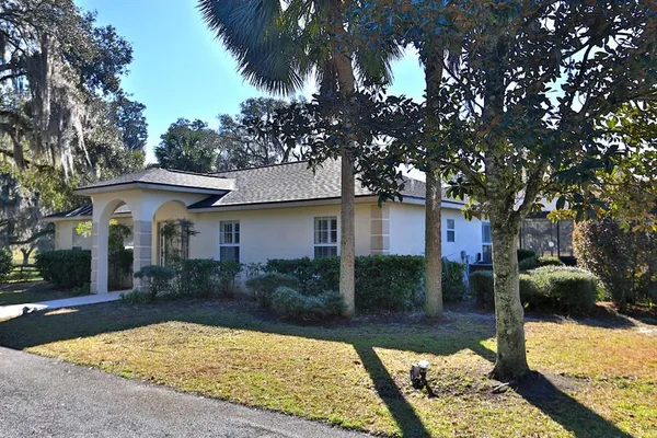 a view of a house with a yard and large tree