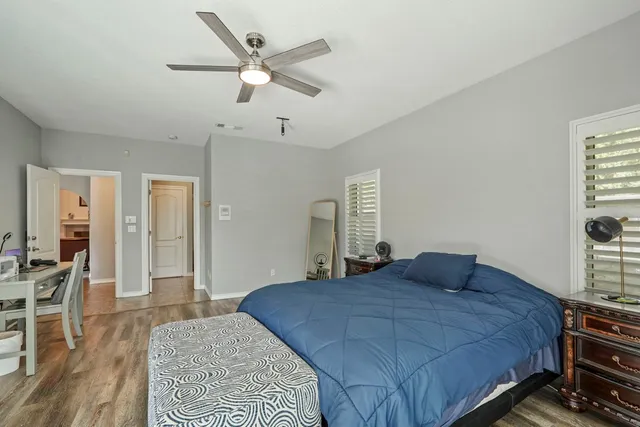 a bedroom with a bed and dresser with wooden floor
