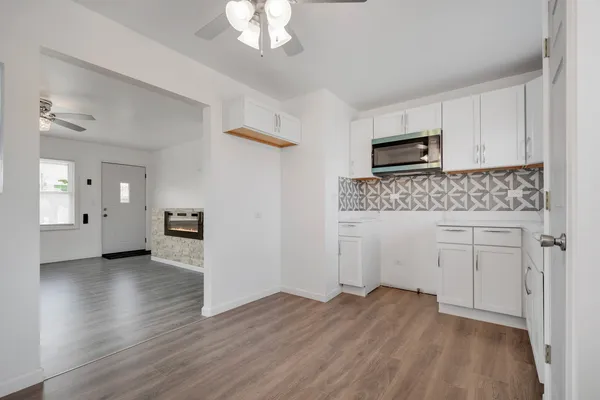 a view of a kitchen with wooden floor electronic appliances and cabinets