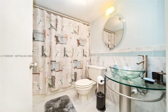 a bathroom with a granite countertop sink a toilet and a mirror