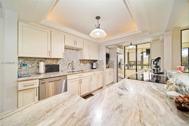 a large white kitchen with cabinets a sink and stainless steel appliances