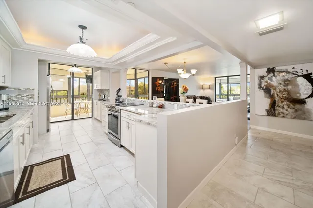 a large white kitchen with granite countertop a large window and white cabinets